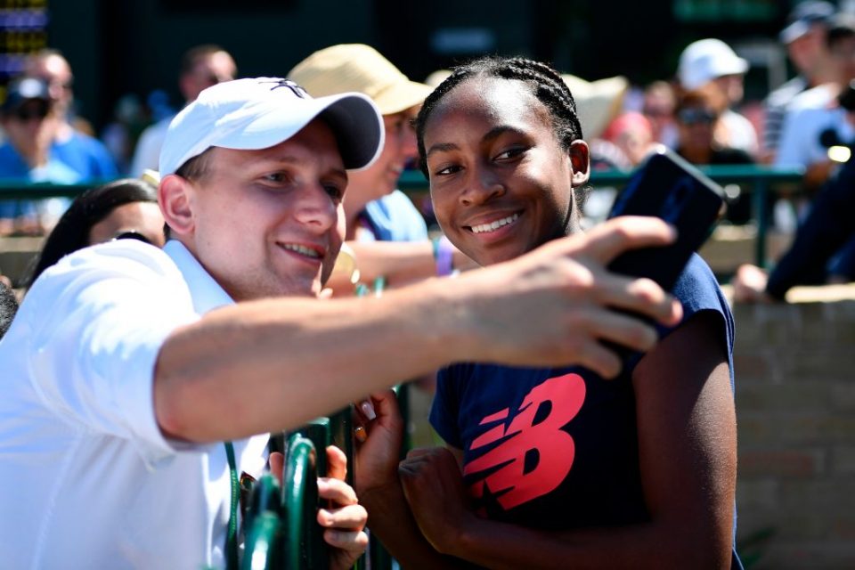 US player Cori Gauff (R) poses for a selfie with fans after a session on the practice courts at The All England Tennis Club in Wimbledon, southwest London, on July 4, 2019, on the fourth day of the 2019 Wimbledon Championships tennis tournament. - Coco Gauff, the 15-year-old schoolgirl who stunned five-time champion Venus Williams in the first round, continued her Wimbledon dream debut on Wednesday when she eased into the last 32 and claimed: "I can beat anyone." Next up for Gauff is a last 32 clash against world number 60 Polona Hercog of Slovenia on July 5. (Photo by Daniel LEAL-OLIVAS / AFP) / RESTRICTED TO EDITORIAL USE        (Photo credit should read DANIEL LEAL-OLIVAS/AFP/Getty Images)