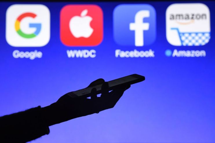 This photograph taken on September 28, 2017, shows a smartphone being operated in front of GAFA logos (acronym for Google, Apple, Facebook and Amazon web giants) as background in H&eacute;d&eacute;-Bazouges, western France. / AFP PHOTO / Damien MEYER (Photo credit should read DAMIEN MEYER/AFP/Getty Images)