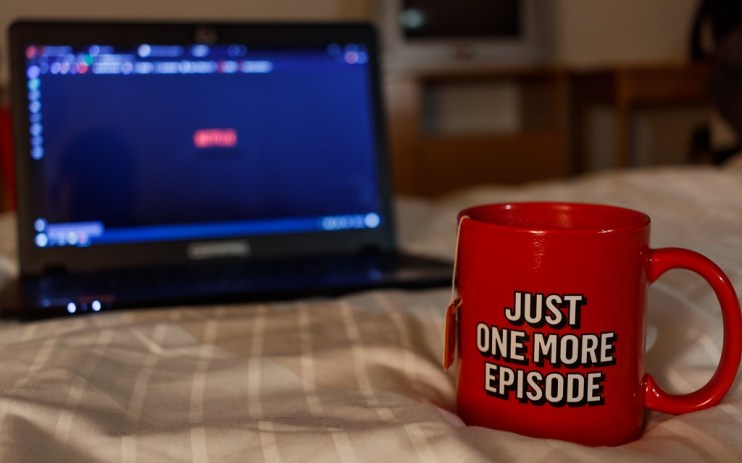 Tea cup and laptop on bed watching Netflix