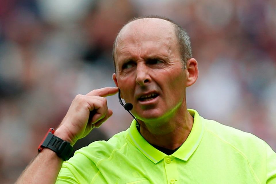 Referee Mike Dean communicates with the VAR (video assistant referee) as a Manchester City penalty, which was saved, is being checked and ruled that it must be retaken during the English Premier League football match between West Ham United and Manchester City at The London Stadium, in east London on August 10, 2019. (Photo by Ian KINGTON / AFP) / RESTRICTED TO EDITORIAL USE. No use with unauthorized audio, video, data, fixture lists, club/league logos or 'live' services. Online in-match use limited to 120 images. An additional 40 images may be used in extra time. No video emulation. Social media in-match use limited to 120 images. An additional 40 images may be used in extra time. No use in betting publications, games or single club/league/player publications. /         (Photo credit should read IAN KINGTON/AFP/Getty Images)