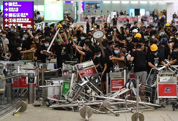 Pro-democracy protestors block the entrance to the airport terminals after a scuffle with police at Hong Kong's international airport on August 13, 2019. - Hundreds of flights were cancelled or suspended at Hong Kong's airport on August 13, 2019 as pro-democracy protesters staged a second disruptive sit-in at the sprawling complex, defying warnings from the city's leader who said they were heading down a "path of no return". The new protest came as Beijing sent further ominous signals that the 10 weeks of unrest must end, with state-run media showing videos of security forces gathering across the border. (Photo by Manan VATSYAYANA / AFP) (Photo credit should read MANAN VATSYAYANA/AFP/Getty Images)