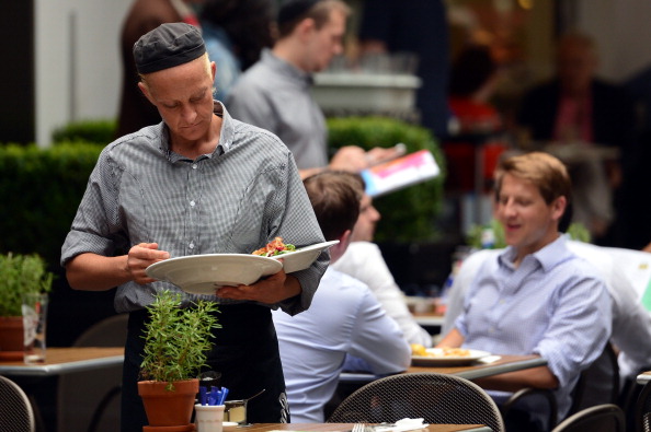 A waitress clears a table at a restaurant in central London, on July 25, 2014. Britain's economy grew strongly in the second quarter, overtaking the size it achieved before the global financial crisis, data showed on Friday in the latest sign of robust recovery. AFP PHOTO / CARL COURT (Photo credit should read CARL COURT/AFP/Getty Images)