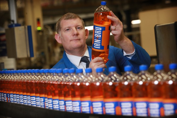 AG Barr CEO Roger White holds up a bottle of Irn-Bru from a factory line of its signature products