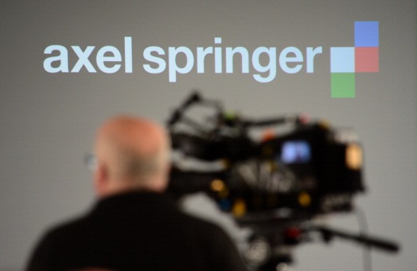 A cameraman films the logo of German media group Axel Springer during the company's annual press conference on March 6, 2014 in Berlin. German media giant Axel Springer said it is expecting higher sales and earnings this year after it met all of its targets in 2013. AFP PHOTO / JOHN MACDOUGALL (Photo credit should read JOHN MACDOUGALL/AFP/Getty Images)