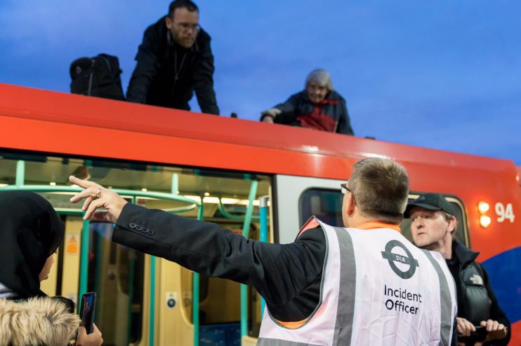 Extinction Rebellion protesters sit on top of a DLR train