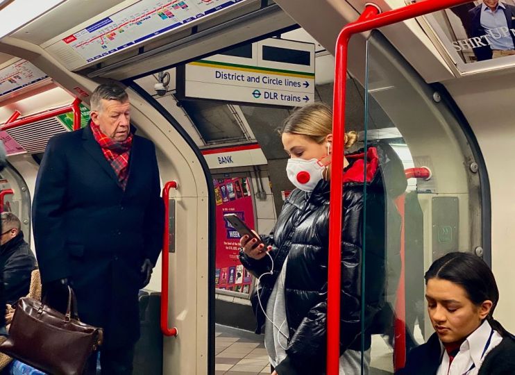 A woman wears a protective face mask on the Tube at Bank station as the number of UK coronavirus cases hit 51