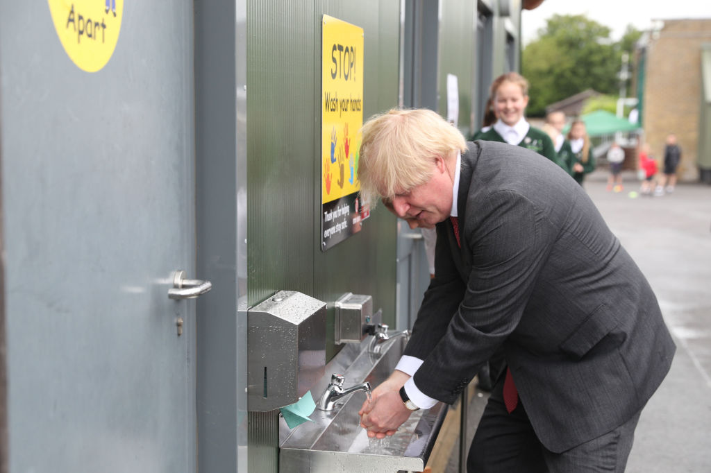 Prime Minister Boris Johnson washes his hands at a sink in the playground during a visit to Bovingdon Primary School in Bovingdon, Hemel Hempstead, Hertfordshire on June 19, 2020