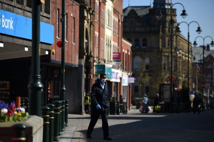 A man wears a mask as he walks along a near deserted street in Oldham during March's lockdown. The area has now re-entered restrictions after a coronavirus spike