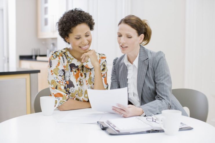 Women discussing investment strategies in a financial office, highlighting the gender confidence gap in UK investing pract...
