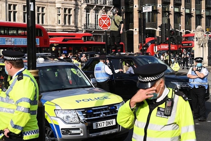 Police in despair as an Extinction Rebellion demonstrator climbs on top of a car and traffic comes to a stop in Parliament Square (Photo by Leon Neal/Getty Images)