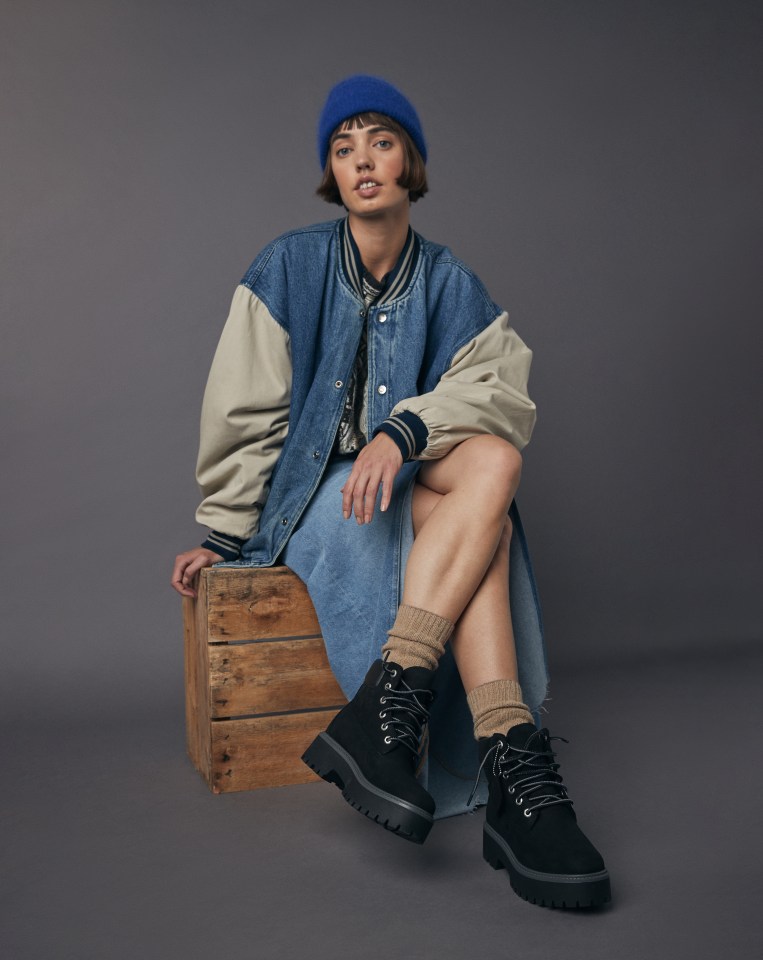 Woman posing on wooden seat, showing her new AllSole footwear.
