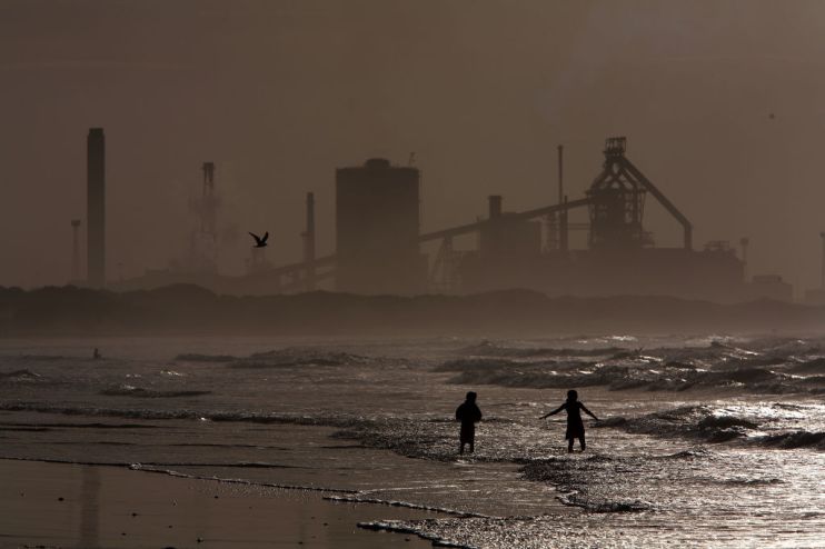 MIDDLESBOROUGH, UNITED KINGDOM - JULY 21: Locals and children play on the surf at high tide on Redcar beach in the shadow of the Corus Steelworks in Teeside, on July 21, 2008, in Middlesborough, England. The giant iron and steel works on the south bank of the River Tees produces 3.4 million tonnes of slab steel a year. (Photo by Christopher Furlong/Getty Images)
