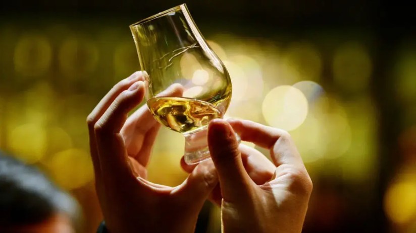 A pair of hands holding a glass of whisky