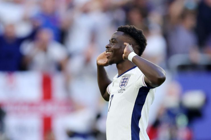 Bukayo Saka cups his ears in celebration