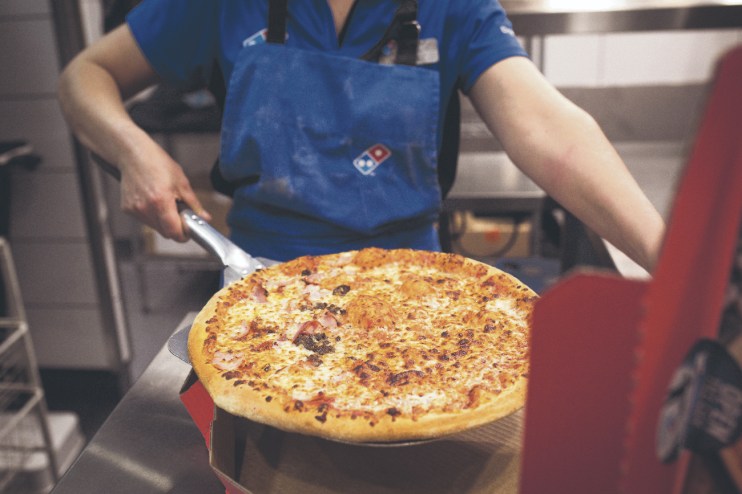 An employee places a cooked pizza into a delivery box inside a Domino's Pizza Group in London. Photographer: Jason Alden/Bloomberg via Getty Images