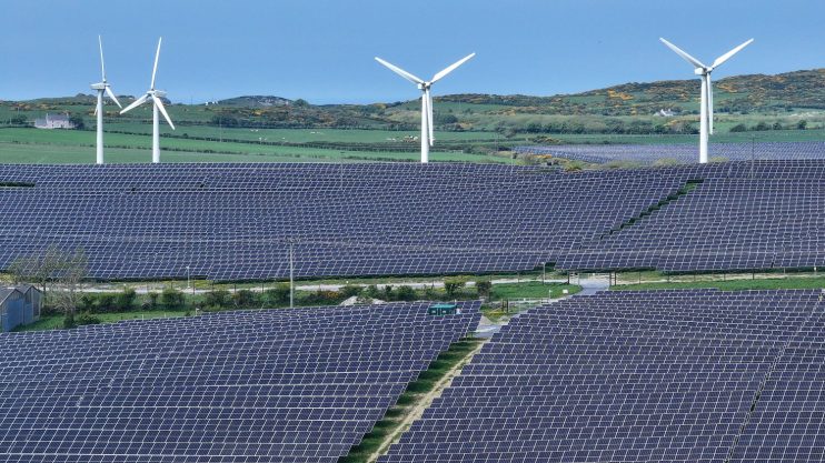 ANGLESEY, WALES - MAY 10: In this aerial view wind turbines can be seen next to the North Anglesey Solar Project at Porth Wen, May 10, 2024 in Anglesey, Wales. Porth Wen is a 50MW Solar and Battery farm completed by Countryside Renewables in 2023. It will contribute to Wales&rsquo; overall goal of the country generating 70% of its electricity consumption from renewables by 2030 and reducing its carbon emissions by at least 95% by 2050. Plans have been submitted to build more solar farms on the island, with a capacity of 350MW which will produce enough energy to power 133,106 homes and cover 12.34 sq km of farmland. (Photo by Christopher Furlong/Getty Images)