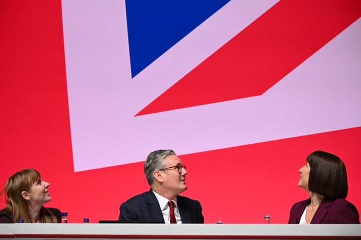 LIVERPOOL, ENGLAND - SEPTEMBER 23: (L-R) Deputy Prime Minister Angela Rayner, Prime Minister Keir Starmer and Chancellor of the Exchequer, Rachel Reeves seen on stage during the Labour Party Conference 2024 at ACC Liverpool on September 23, 2024 in Liverpool, England. This is Labour's first conference since they were returned as the governing party of The UK and Northern Ireland by voters in the July election, ending 14 years of Conservative rule. They won with a landslide majority of 172 seats, and 412 in total. (Photo by Leon Neal/Getty Images)