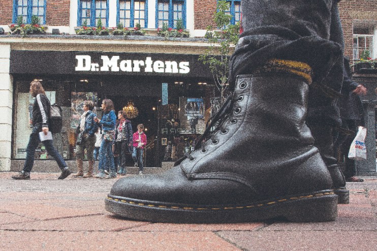 (A pedestrian wearing Dr. Martens boots poses for a photograph outside the footwear company's store in Convent Garden in London (Photographer: Simon Dawson/Bloomberg via Getty Images))