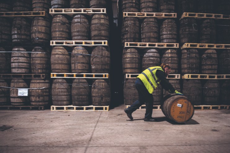 Workers fill casks that will be stored at the distillery for a minimum of three years before the product can be called Scotch Whisky at the whisky Annandale Distillery, in Annan, in Dumfries and Galloway, in Scotland. (Photo by Andy Buchanan / AFP) (Photo by ANDY BUCHANAN/AFP via Getty Images)