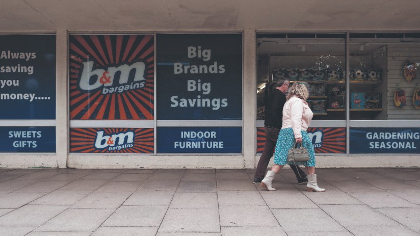 Members of the public walks past a branch of high street retailer B&M advertising big brands and big savings. (photo by Daniel Harvey Gonzalez/In Pictures via Getty Images)