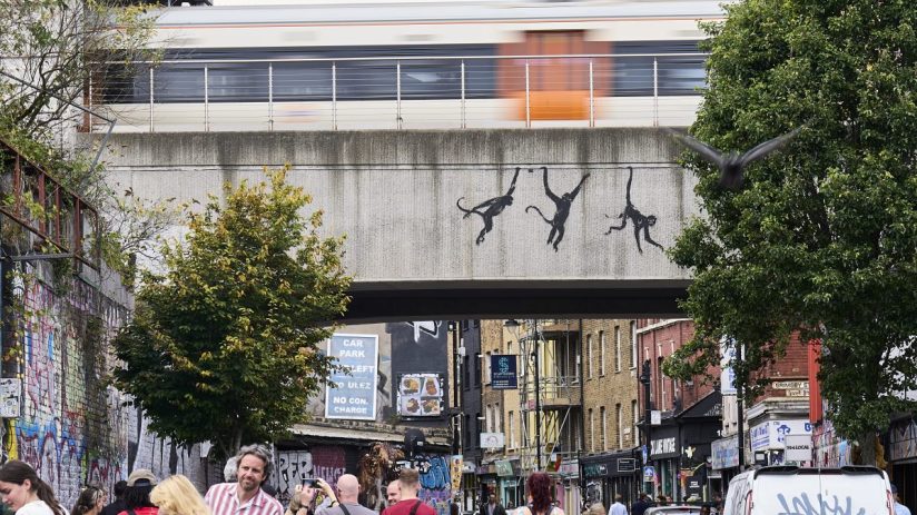 LONDON, ENGLAND - AUGUST 07: An artwork featuring three monkeys by Banksy, adorns a bridge over Brick Lane on August 07, 2024 of London, England. The elusive street artist posted a picture of the artwork earlier today on his Instagram account, his usual method of claiming credit. It came after he debuted two other works in London in as many days. (Photo by Aitor Alcalde/Getty Images)