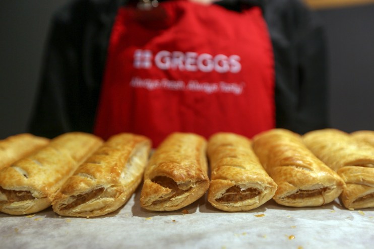Greggs storefront with customers, highlighting challenges amid a 7.4% sales rise and economic impact on shares.