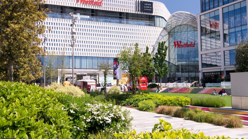 The company behind the Westfield shopping centres in London has reduced its pre-tax loss.