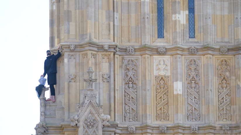 People watch a man with a Palestine flag after he climbed up Elizabeth Tower, which houses Big Ben at the Palace of Westminster in London. Picture date: Saturday March 8, 2025. James Manning/PA Wire Copyright notice: &copy; 2025 PA Media, All Rights Reserved