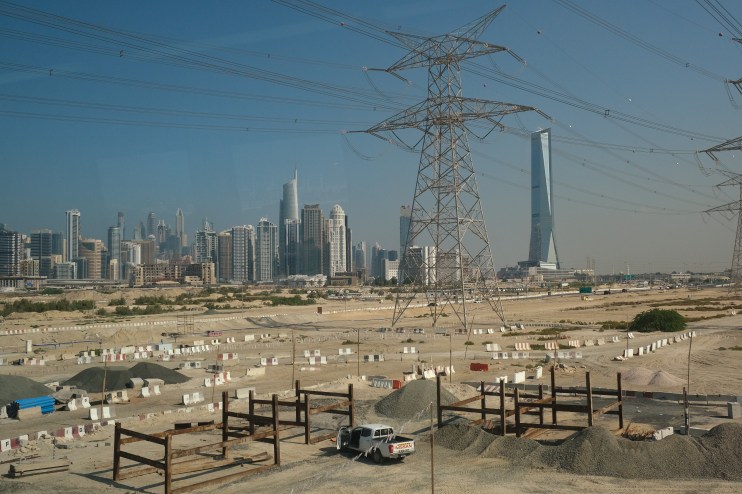 DUBAI, UNITED ARAB EMIRATES - DECEMBER 07: In this view through a metro train window high-rise buildings stand behind electricity power lines and a transmission tower on December 07, 2023 in Dubai, United Arab Emirates. Dubai is one of the seven emirates in the UAE and has become a popular tourist destination. (Photo by Sean Gallup/Getty Images)