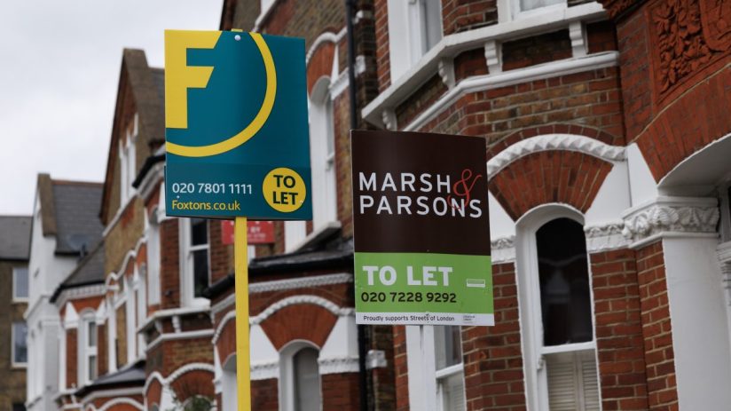 First time buyers celebrating in front of a sold sign, representing a significant increase in mortgage borrowing in 2025.
