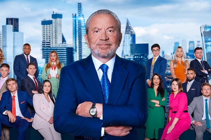 Lord Sugar with Apprentice 2026 cast members in a boardroom setting, featuring modern decor and business attire.