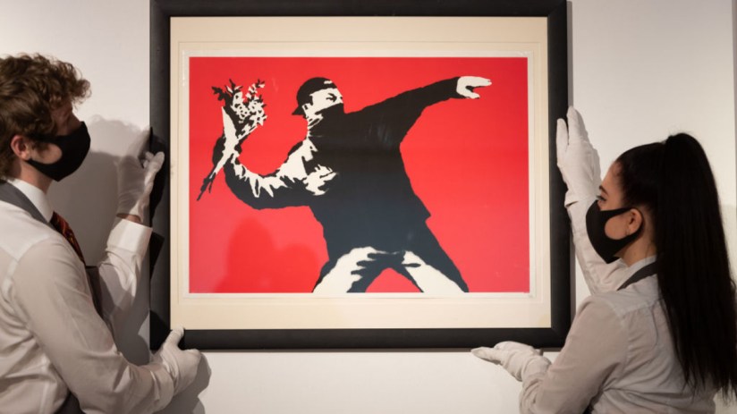 Love is in the Air by Banksy is displayed during preparations ahead of online sales at Christie's Auction House in 2021 in London. (Photo by Ian Gavan/Getty Images)