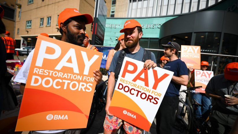 BRISTOL, ENGLAND - JULY 25: Striking doctors protest outside Bristol Royal Infirmary hospital on July 25, 2025 in Bristol, England. Resident doctors, formerly called junior doctors, have begun a five-day strike in England over a pay dispute with the government. Members of the British Medical Association (BMA) said earlier this week that they would go ahead with the strike, after talks with the government failed to reach an agreement over the doctors' demands for 'pay restoration.' Despite receiving an average 5.4% pay rise for this financial year and a 22% increase over the previous two years, the BMA says the Health secretary Wes Streeting said: "These strikes were unnecessary." (Photo by Finnbarr Webster/Getty Images)