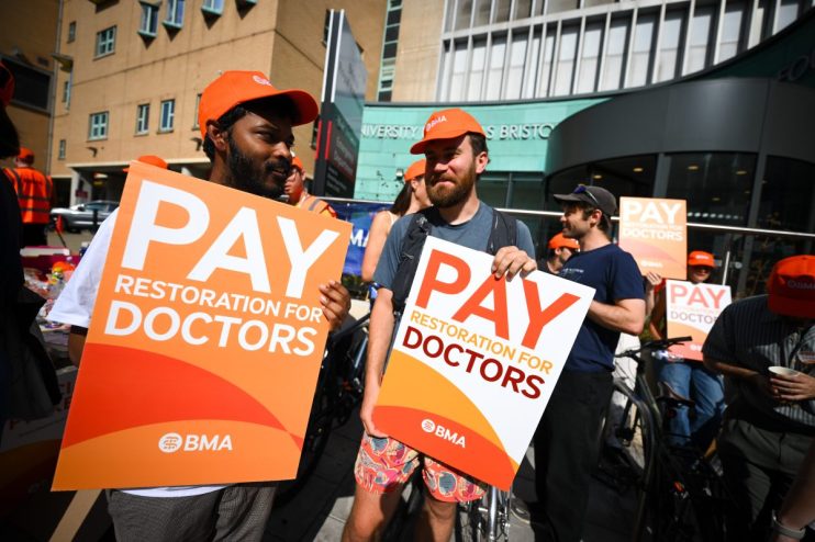 BRISTOL, ENGLAND - JULY 25: Striking doctors protest outside Bristol Royal Infirmary hospital on July 25, 2025 in Bristol, England. Resident doctors, formerly called junior doctors, have begun a five-day strike in England over a pay dispute with the government. Members of the British Medical Association (BMA) said earlier this week that they would go ahead with the strike, after talks with the government failed to reach an agreement over the doctors' demands for 'pay restoration.' Despite receiving an average 5.4% pay rise for this financial year and a 22% increase over the previous two years, the BMA says the Health secretary Wes Streeting said: "These strikes were unnecessary." (Photo by Finnbarr Webster/Getty Images)
