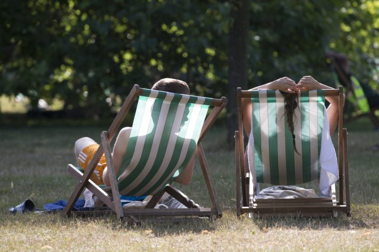 LONDON, ENGLAND - JULY 18: A couple relax on deckchairs in the warm weather in Hyde Park on July 18, 2014 in London, England. The Met Office has issued a heatwave alert as temperatures soar to their highest of the year. (Photo by Oli Scarff/Getty Images)