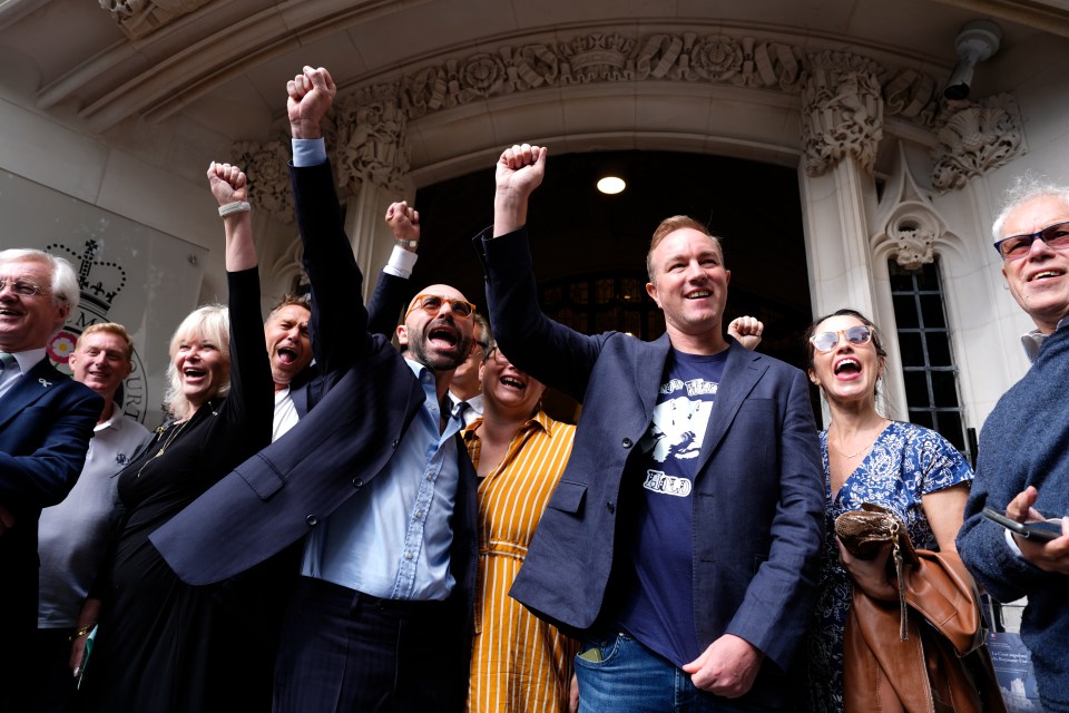 two men outside the supreme court with their hands in the air