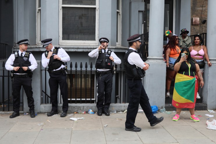 LONDON, ENGLAND - AUGUST 25: A police officer yawns as he stands amongst other officers while revellers attend Notting Hill Carnival on August 25, 2024 in London, United Kingdom. Sunday is known to be family-friendly with the Children's Parade taking place culminating in the children's mas. The Notting Hill Carnival celebrating Caribbean culture has taken place over the summer bank holiday most years since 1966. (Photo by Alishia Abodunde/Getty Images)