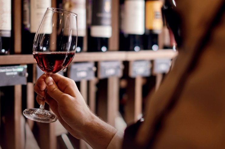 A glass of red wine on a table, symbolizing the ongoing sexism and bigotry in the wine industry highlighted in the article.