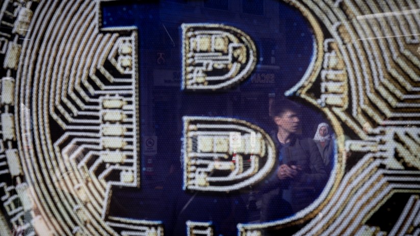 ISTANBUL, TURKEY - NOVEMBER 08: People are reflected in a Bitcoin sign at the entrance of a cryptocurrency exchange office on November 08, 2024 in Istanbul, Turkey. Bitcoin has soared to new record highs nearing 77,000 in the days after Donald Trump's re-election and on his campaign promise to support Bitcoin and the cryptocurrency market. (Photo by Chris McGrath/Getty Images)
