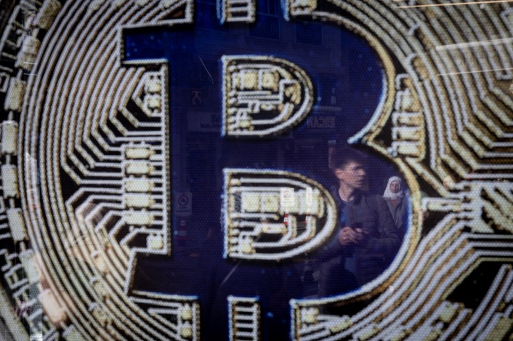 ISTANBUL, TURKEY - NOVEMBER 08: People are reflected in a Bitcoin sign at the entrance of a cryptocurrency exchange office on November 08, 2024 in Istanbul, Turkey. Bitcoin has soared to new record highs nearing 77,000 in the days after Donald Trump's re-election and on his campaign promise to support Bitcoin and the cryptocurrency market. (Photo by Chris McGrath/Getty Images)
