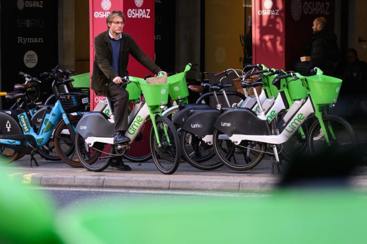 LONDON, ENGLAND - NOVEMBER 26: A man hires a Lime rental e-bike on November 26, 2024 in London, England. Transport For London may take enforcement action against companies providing e-scooters and e-bikes to tackle poorly parked vehicles that cause access or safety issues. Transport for London has allocated around &pound;1million to allow boroughs to create 7,500 new parking spaces, while also creating 800 parking bays along the red route network. Rental companies who fail to enforce stricter parking regulations may see their e-bikes confiscated. (Photo by Leon Neal/Getty Images)