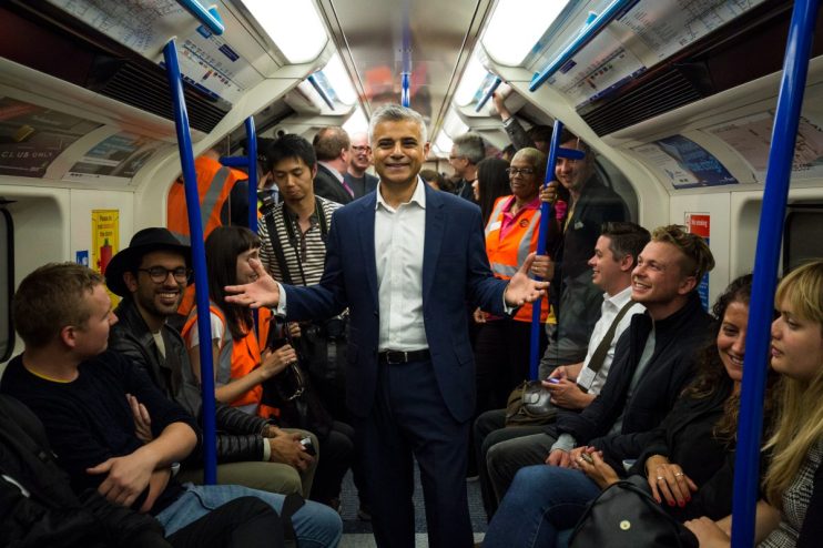 LONDON, ENGLAND - AUGUST 20: London Mayor Sadiq Khan extends his hands as his stand between passengers in the first Night Tube train along the Victoria line on August 20, 2016 in London, England. The London Underground's 24-hour service begins for the first time in its 153 year history. The new Night Tube will see both the Victoria and Central lines run through the night on Fridays and Saturdays. (Photo by Jack Taylor/Getty Images)