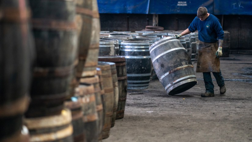 A worker is seen inspecting a whisky cask at Speyside Cooperage
