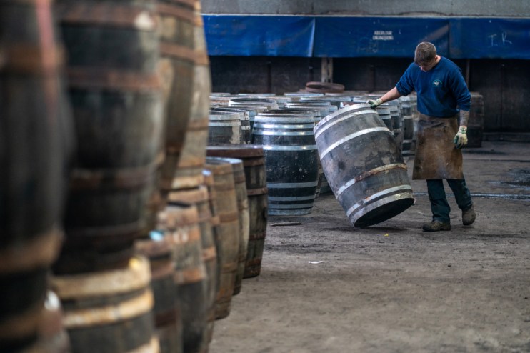 A worker is seen inspecting a whisky cask at Speyside Cooperage