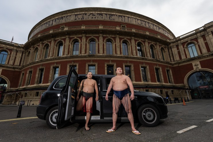 DECEMBER 04: Sumo Wrestlers Kitanowaka Daisuke and Fukutsuumi Akira of Japan pose with a London Black Cab following The Grand Sumo Tournament press conference at Royal Albert Hall on December 04, 2024 in London, England. (Photo by Ryan Pierse/Getty Images)