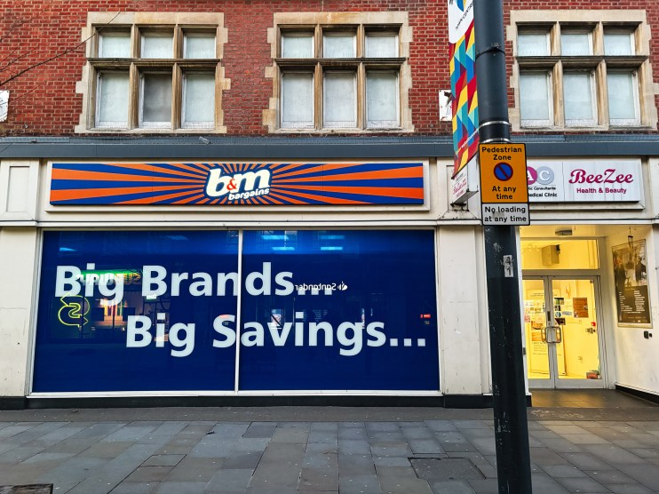 B&M storefront with declining stock trends graph, reflecting operational weakness and profit drop in retail business news.