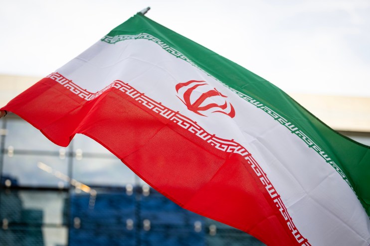 Iranian national flag waving against a clear sky, symbolizing national pride and identity in current geopolitical climate