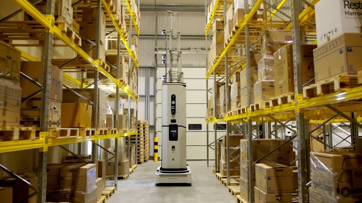 Robot scanning inventory racks for efficient warehouse management and automation in industrial logistics setting.