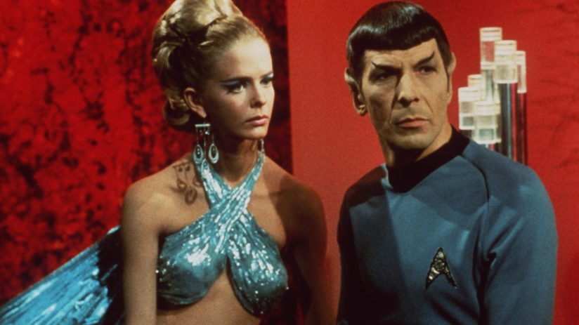 Spock from Star Trek in a classic pose with raised eyebrow, wearing a Starfleet uniform against a futuristic starship back...