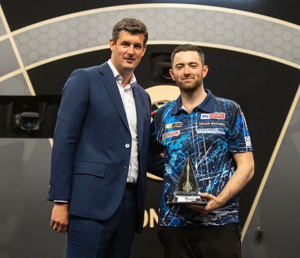 Porter and Humphries celebrate 2024 PL17 final victory with trophy, smiling and embracing on stage in business attire